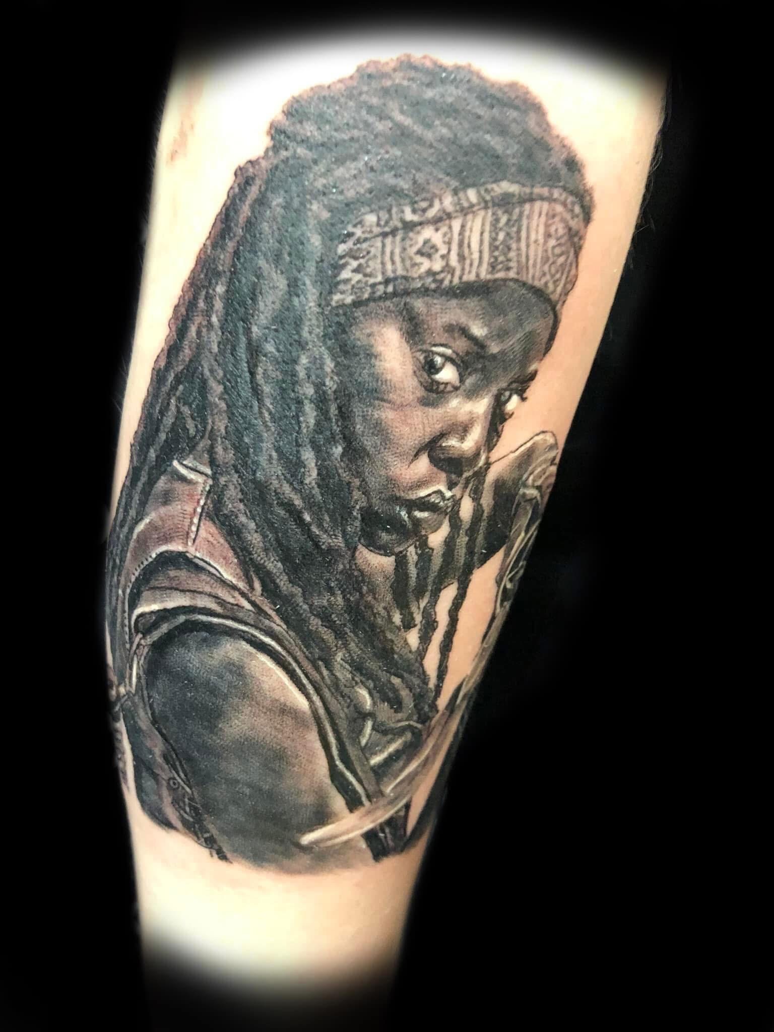 Black and grey realistic portrait of Michonne from The Walking Dead on forearm by Jin