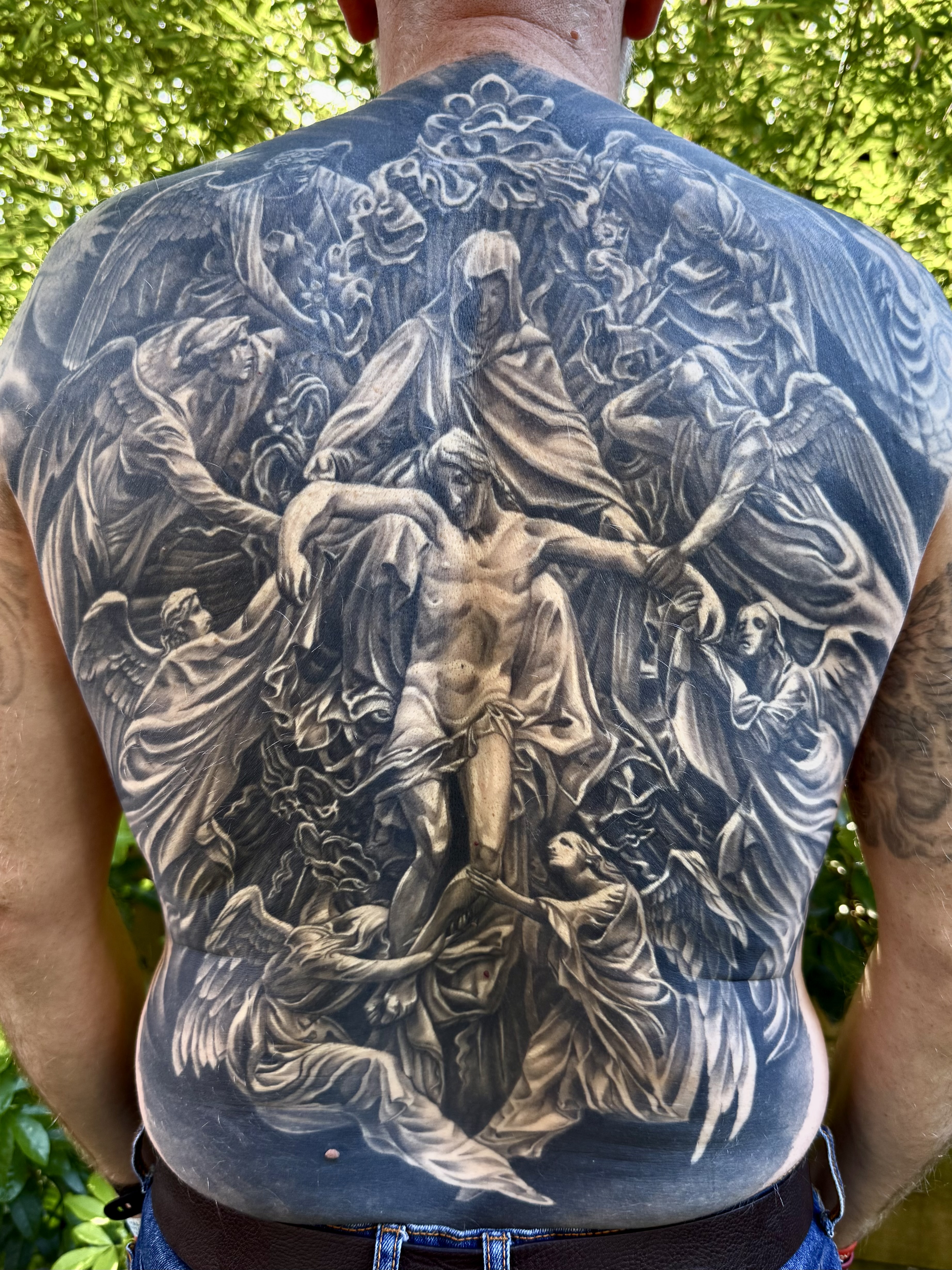 Black and grey Renaissance-style religious scene full back piece with angels and crucifixion by Ray